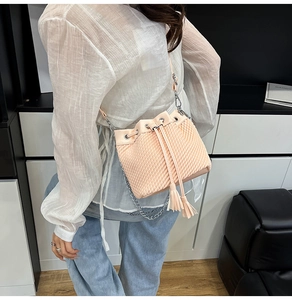 Detailed close-up of pink pleated bucket bag featuring stylish tassels and silver metal chain