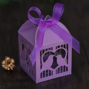 Gros plan d'une boîte à dragées violette découpée au laser avec ruban et oiseaux