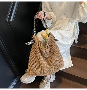 Detail of woven straw tote bag with black and white striped handles and yellow tulips