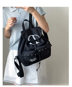 Detail of black nylon backpack featuring silver studs and white V logo on the flap