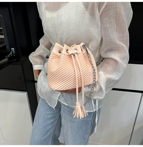 Macro detail of peach bucket bag with quilted texture, silver eyelets and tassel drawstring