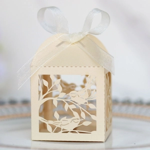 Detail of laser-cut lovebird pattern on ivory favor box with white organza ribbon bow