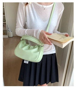 Detail of light green pleated cloud bag featuring woven handle and soft PU texture