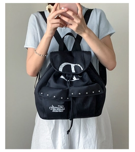 Detail of black canvas backpack with drawstring closure and silver rivet stud pockets