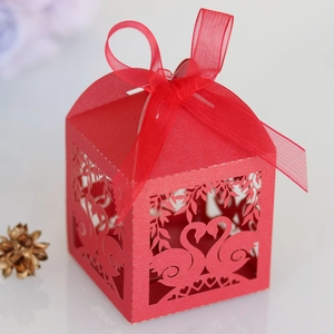 Detailed laser-cut red wedding favor box with swan heart pattern and sheer ribbon bow