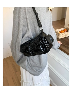 Détail du sac à bandoulière noir avec nœud, poches fonctionnelles et boucles argentées