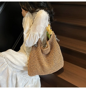 Detailed close-up of woven straw tote bag with black and white striped handles on wooden stairs