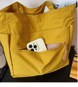 Detail of yellow tote bag showing zipped front pocket and large storage capacity