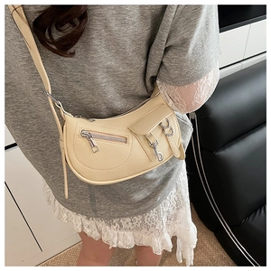 Detail of a beige crescent moon bag with lychee texture and metallic zip accents