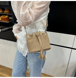 Detail of camel bucket bag featuring woven texture with drawstring and tassel accent