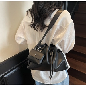 Detail of black leather bucket bag with drawstring closure and matching mini pouch