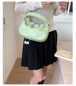 Detail of mint green pleated dumpling bag with chunky woven handle and shoulder strap