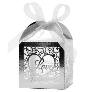 Macro shot of silver pearl paper favor box with laser-cut Love motif and organza ribbon
