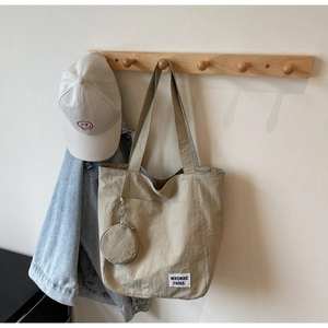 Detail of khaki canvas tote bag with small round coin purse and white woven label