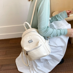 Détail d'un mini sac à dos en similicuir crème avec fermeture éclair métallique argentée