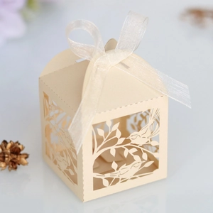 Macro detail of laser-cut lovebird pattern on cream paper wedding gift box with ribbon