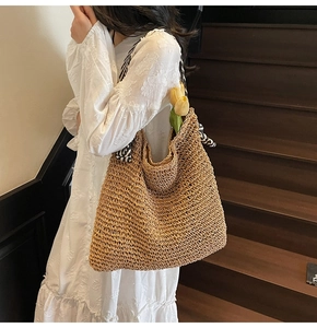 Detail of hand-woven hollow straw tote bag featuring stylish black and white striped handles