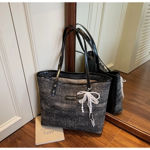 Detail of tweed tote bag featuring white lace bow and pearl pendant near mirror