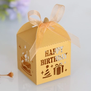 Detail of laser-cut Happy Birthday gold candy box with sheer ribbon and party icons