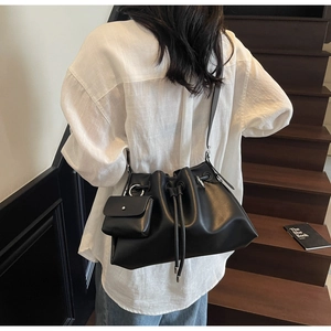 Detail of a black matte bucket bag with a small pouch on a stylish female model