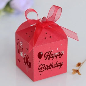 Macro shot of red laser-cut Happy Birthday gift box with elegant ribbon and hollow pattern
