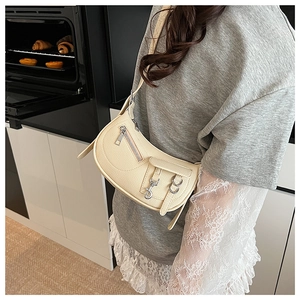 Detail of cream white half-moon bag with lychee texture leather and silver zippers