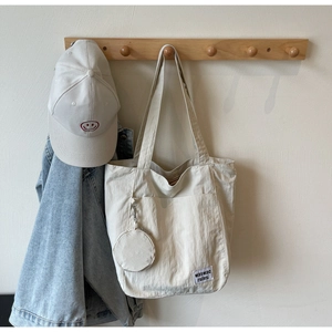 Detail of beige nylon tote bag with waswac embroidery and matching round coin purse