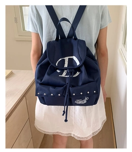 Detail of navy canvas backpack with white D print, drawstring closure and dual front pockets