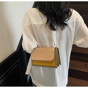 Detail view of tri-color flap crossbody bag with gold chain strap on model