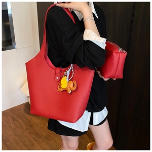 Detail of red leather tote bag featuring a lychee texture and cute elephant charm