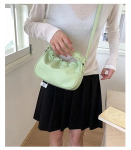 Detail of mint green pleated cloud bag with woven handle and thin shoulder strap
