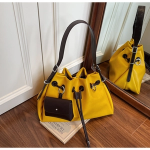 Detail of yellow tote bag featuring a brown wide strap and matching hanging coin purse