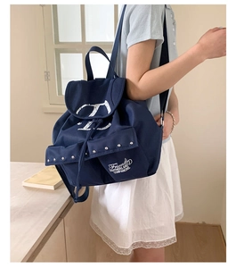 Vue détaillée du sac à dos en toile bleu marine avec logo V et rivets métalliques
