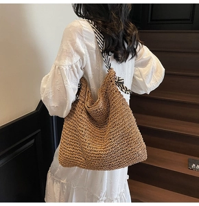 Close-up of woven shoulder bag with striped ribbon strap on white dress model