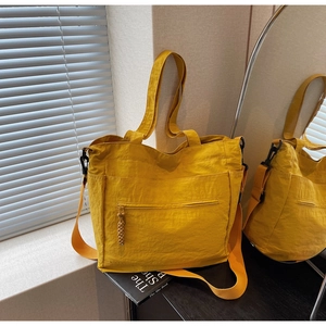Detailed close-up of large yellow nylon tote bag with textured fabric and functional pockets