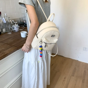 Détail du sac à dos en cuir crème avec texture litchi et pendentif LOVE coloré