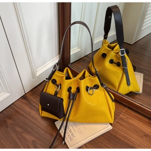 Detail of yellow drawstring bucket bag with dark brown straps and mini hanging coin purse