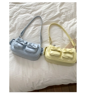 Sacs portés épaule bleu clair et jaune avec nœuds sur fond de draps blancs