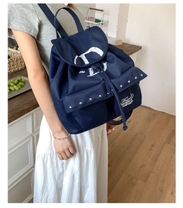 Detail of dark blue nylon backpack with drawstring flap and white art text prints