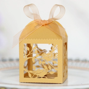 Detailed laser-cut bird pattern on golden wedding favor box with a ribbon bow