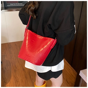 Classic bright red crocodile pattern bucket bag shown from a side perspective on model