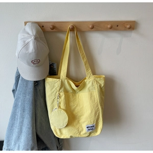 Detail of yellow canvas tote bag with hanging coin purse on a wooden hook