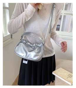 Detail of silver metallic pleated cloud bag with woven handle and tag for chic commute