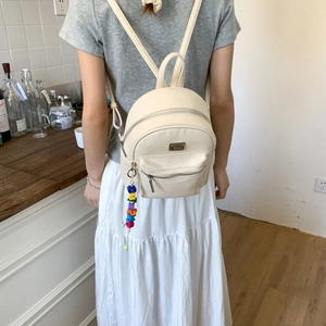 Détail du sac à dos en similicuir crème avec texture et charm en perles colorées