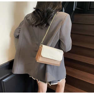 Detailed shot of a tricolor flap crossbody bag with a gold chain strap on model