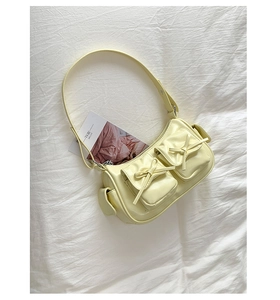 Vue de dessus du sac à bandoulière jaune à nœuds sur tissu blanc avec magazine déco