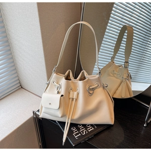 Detail of a creamy white bucket bag with a matching mini pouch and silver metal rings
