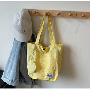 Detail of yellow tote bag with a small round matching pouch on a wooden hanger