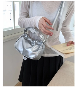 Detail of silver metallic pleated cloud bag with woven handle and thin shoulder strap