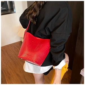 Detail view of red crocodile pattern bucket bag with protective metal feet at the bottom